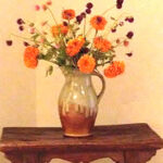 Orange flowers in a vase sitting on a wall shelf